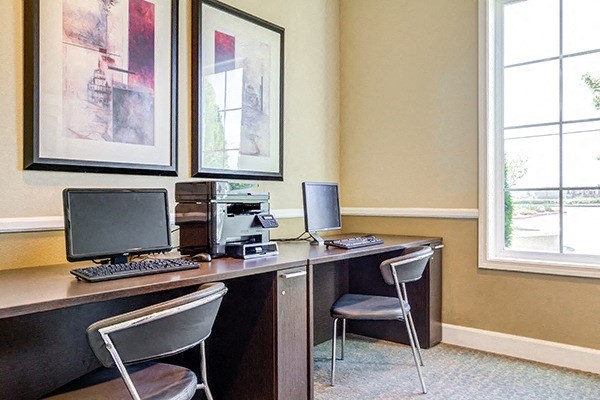 a room with a desk with a computer and chairs