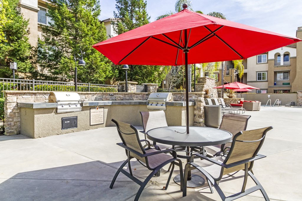 a patio with a table and chairs with a red umbrella