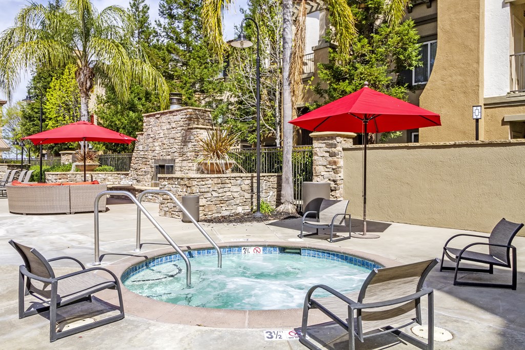 a small pool with chairs and umbrellas next to a building