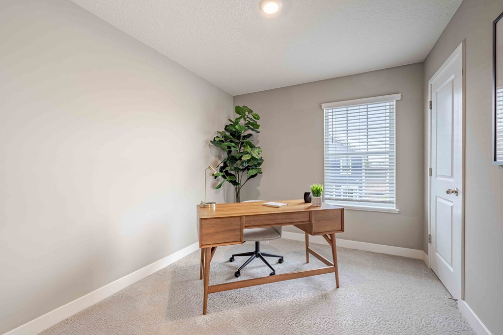 a home office with a wooden desk and a window