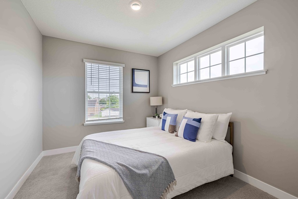 a bedroom with a bed and two windows