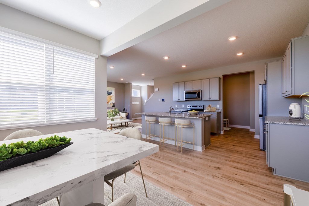 an open kitchen and dining room with a marble counter top and a table with chairs