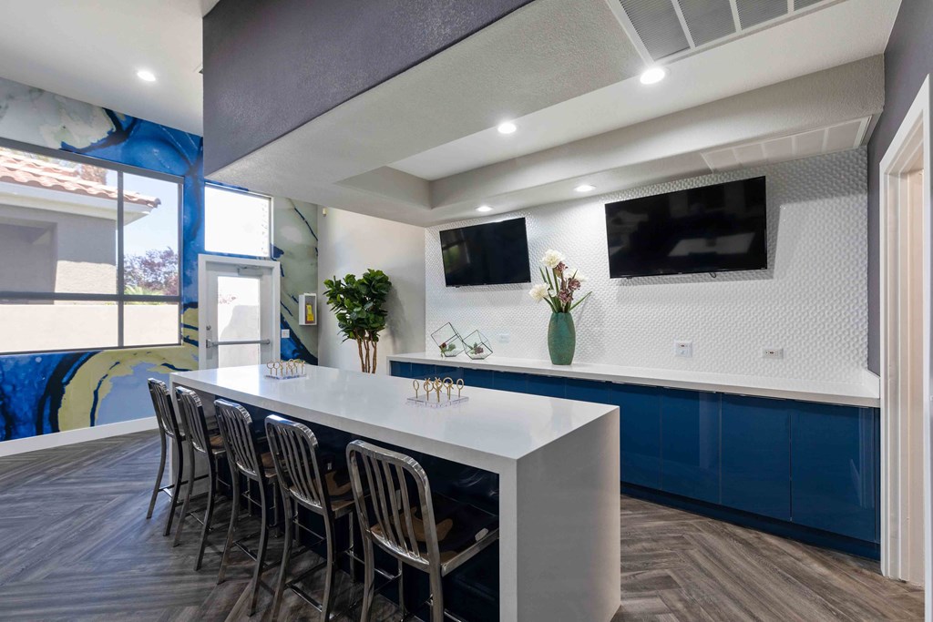a kitchen with a counter and chairs and a tv