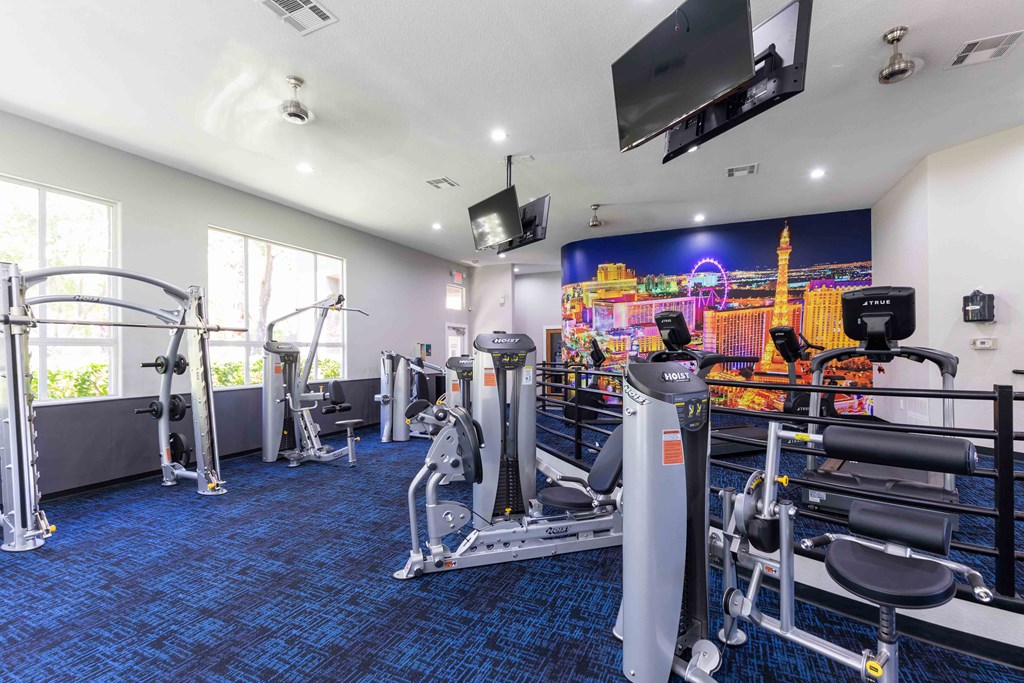 a gym with weights and cardio equipment in a room with windows