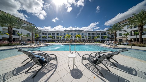 a swimming pool with lounge chairs in front of an apartment building