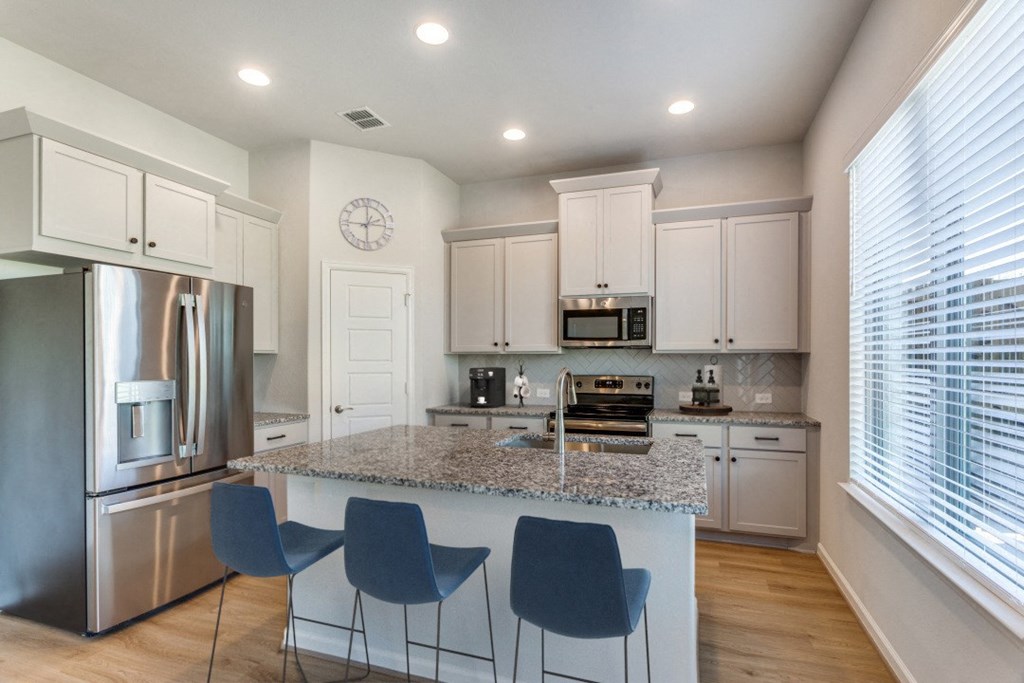 A kitchen with a granite countertop and blue chairs.