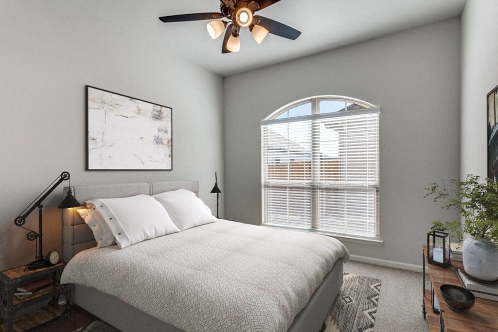 A bedroom with a bed, a ceiling fan, and a window with blinds.