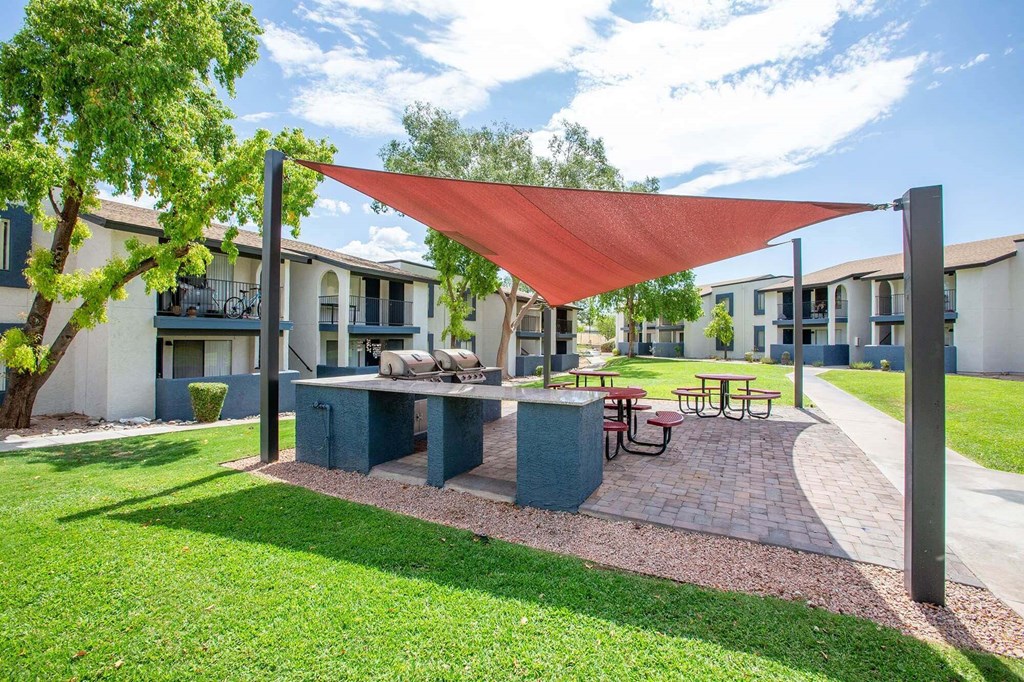 a patio with a picnic table and a red canopy