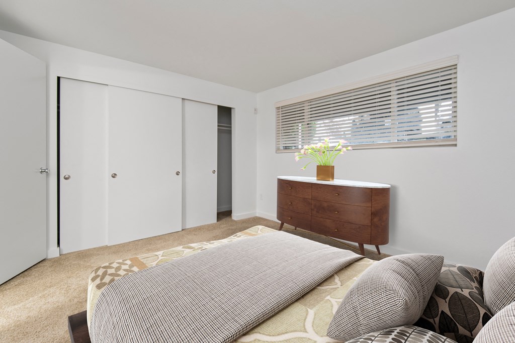 a bedroom with a bed and a dresser and a window