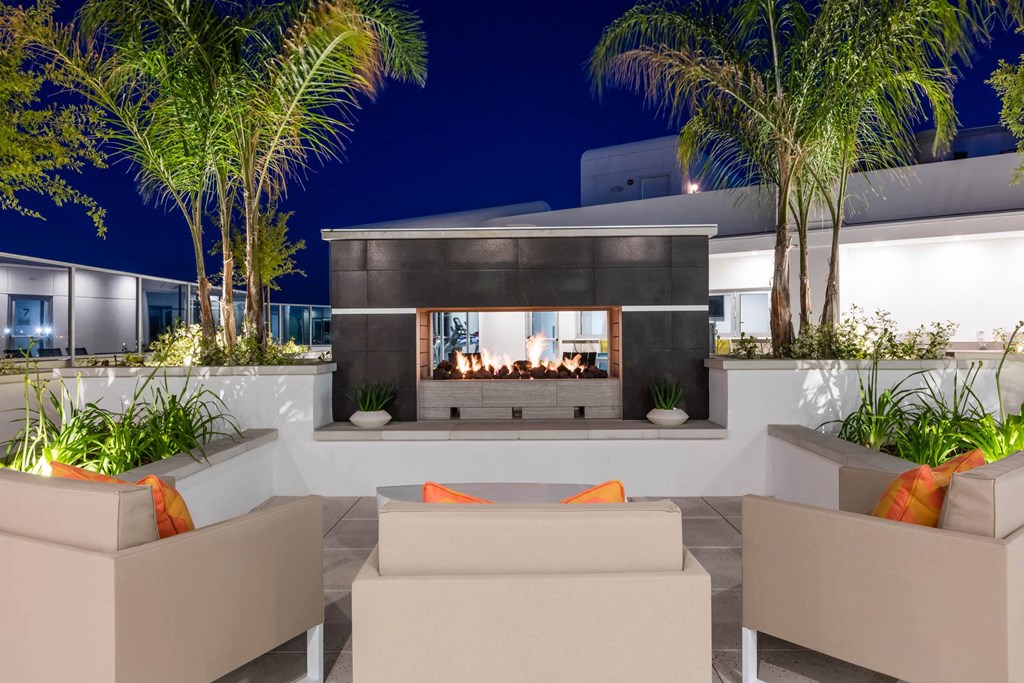 a patio with couches and a fire pit at night