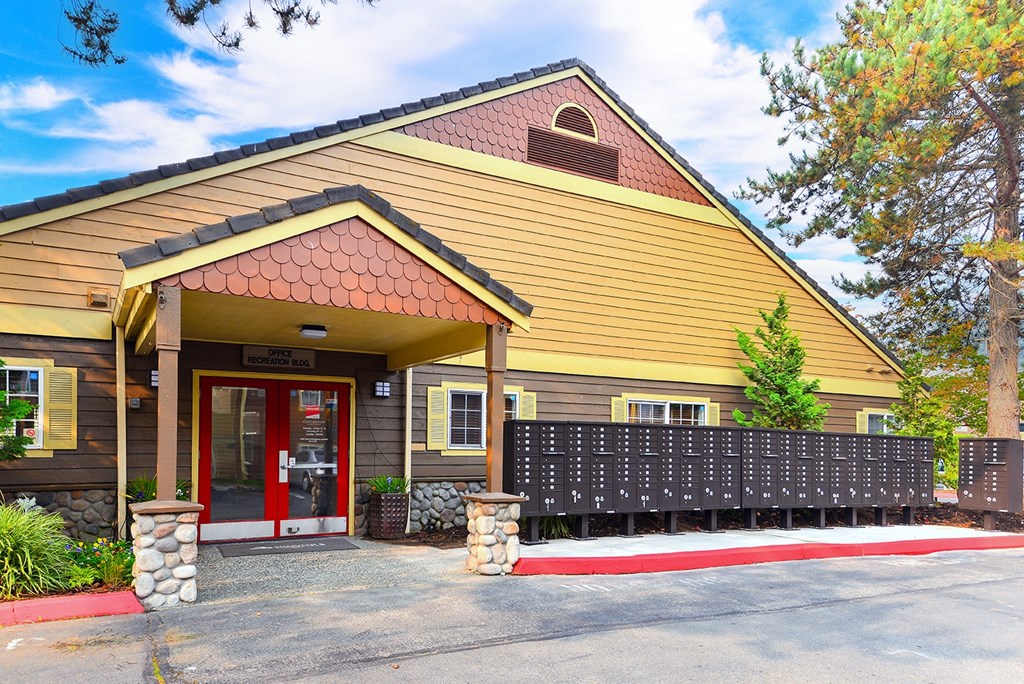 the front of a yellow building with a red door and a porch