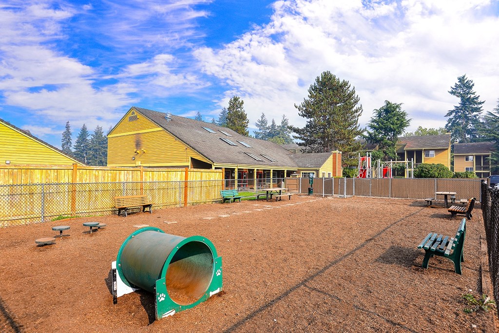 a fenced in play area with a playground and benches
