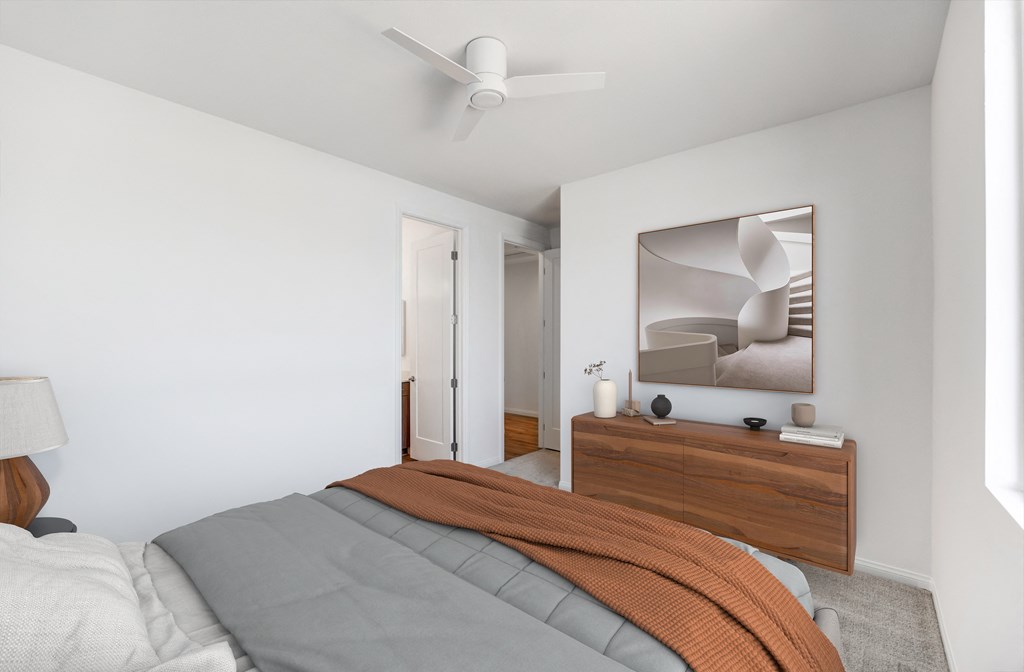 a bedroom with white walls and a bed with an orange blanket