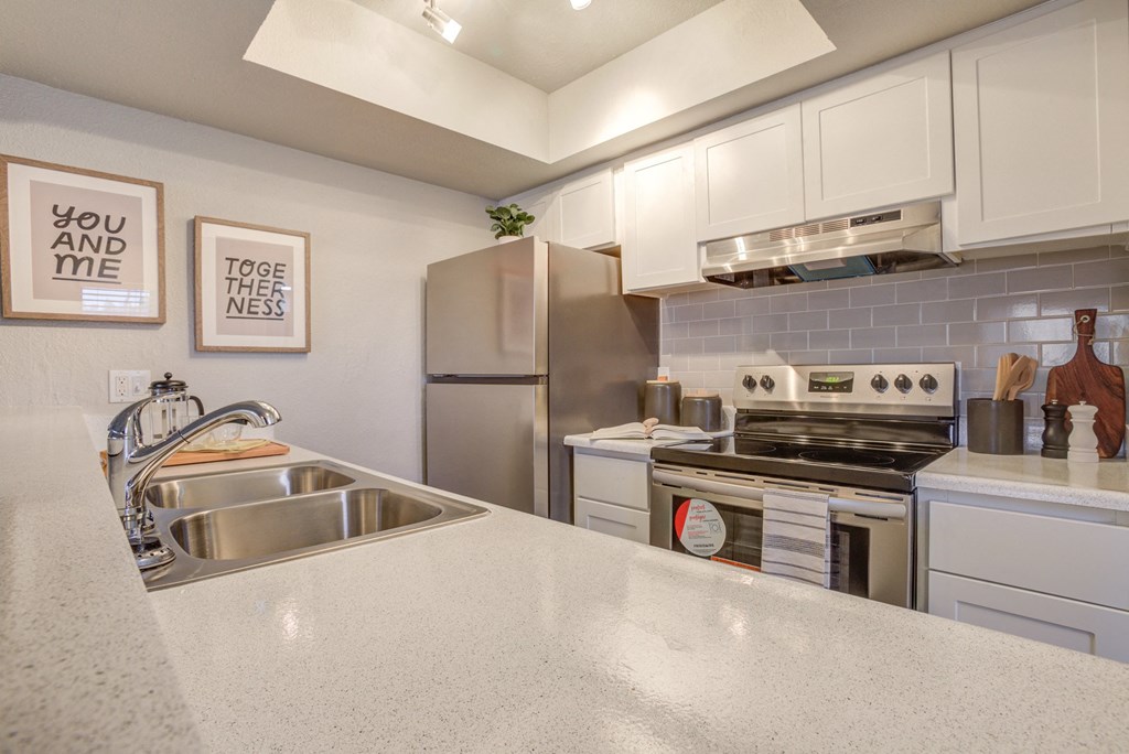 2-Bedroom Apartments in North Mountain Village, Phoenix, AZ - Ardella on 28th - Modern Kitchen with Stainless Steel Appliances, White Cabinetry, Grey Tile Backsplash, and White Counters