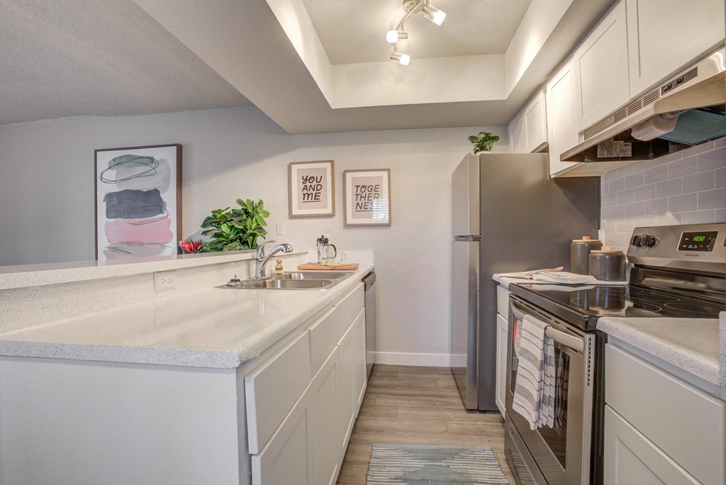 Three Bedroom Apartments in Phoenix, AZ - Adrella on 28th - Kitchen with White Countertops, Stainless Steel Appliances, and Track Lighting.