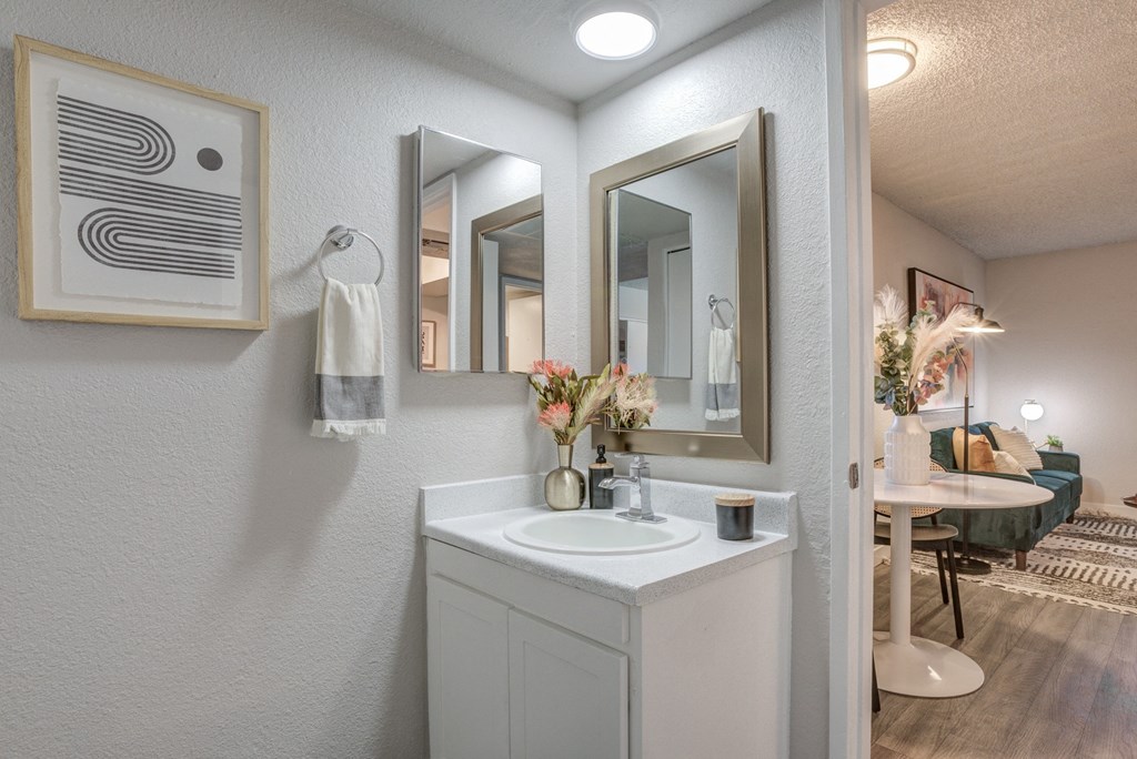 a bathroom with a sink and three mirrors on the wall