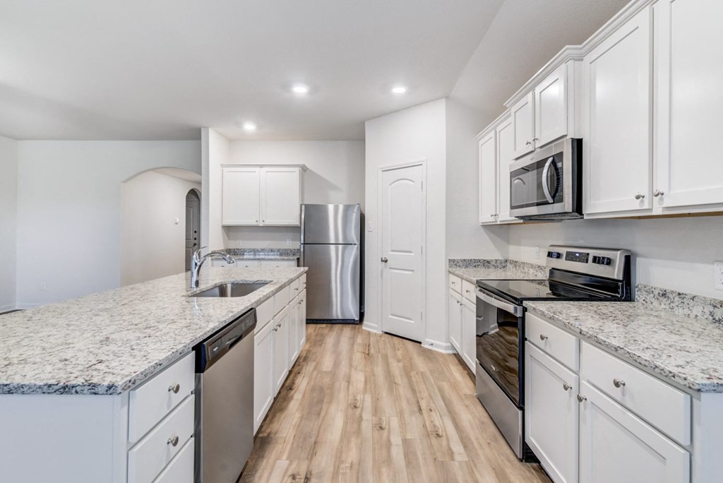 Three-BR Homes For Rent In Denton, TX - Beall Way - Kitchen With Stainless Steel Appliances, Granite Countertops, Kitchen Island, And White Cabinets For Lots Of Storage Space