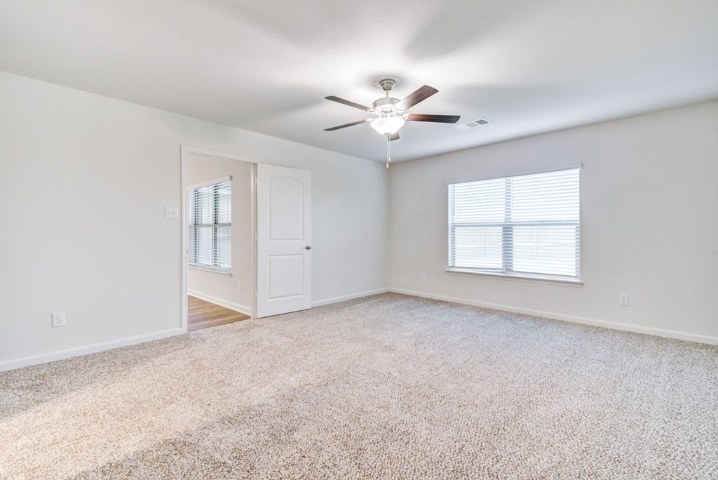 an empty living room with a ceiling fan and a window