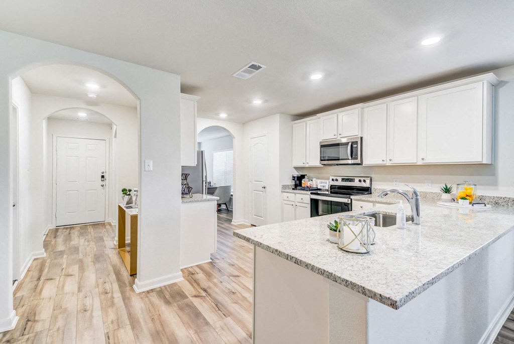 a kitchen with white cabinets and a marble counter top