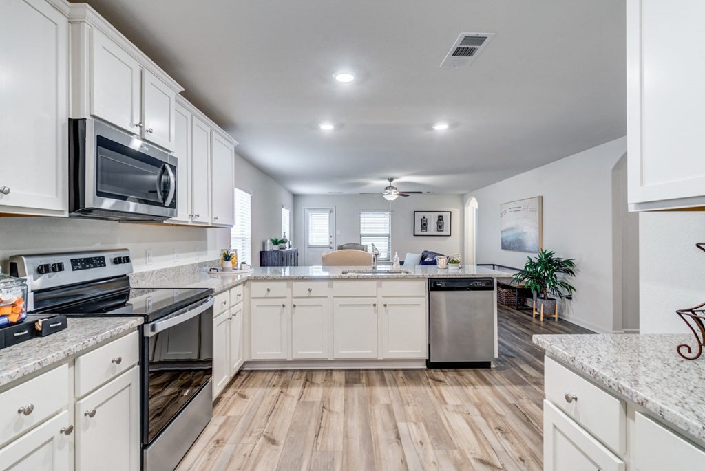a large kitchen with white cabinets and stainless steel appliances