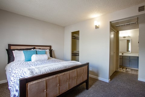 1-Bedroom Apartments in Tucson, AZ - Peaks at Redington - Bedroom with Carpeted Floor, Full-Size Bed, Spacious Closet with Clothes Hangers, and Attached Bathroom.