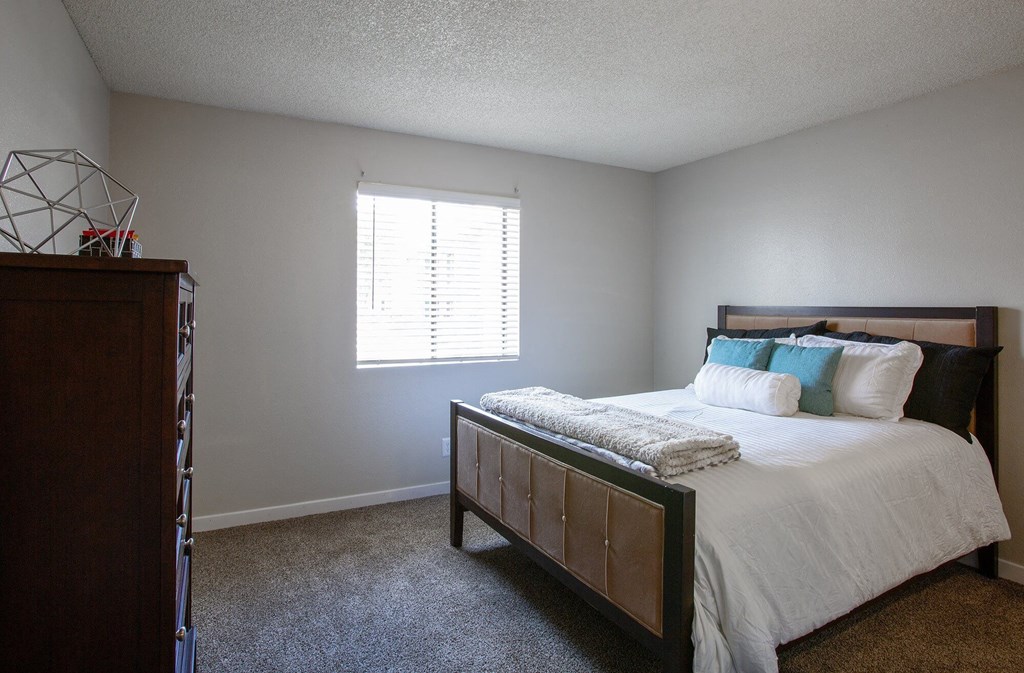 a bedroom with a bed and a dresser and a window