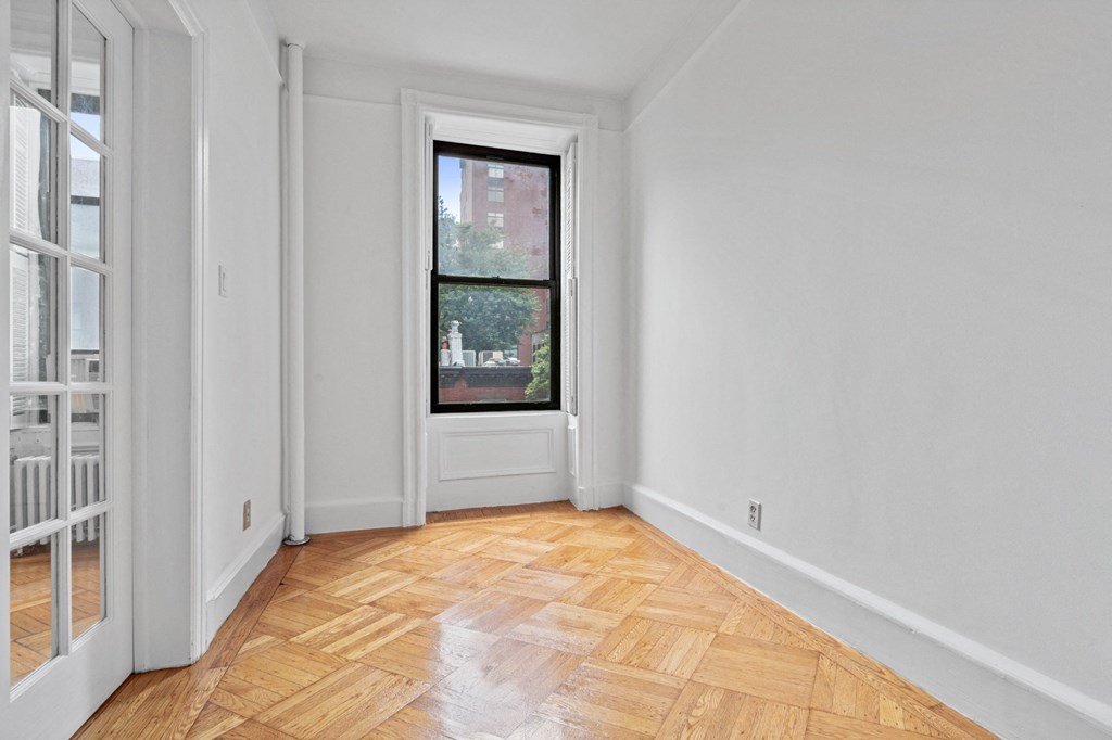 an empty room with a window and wooden floors