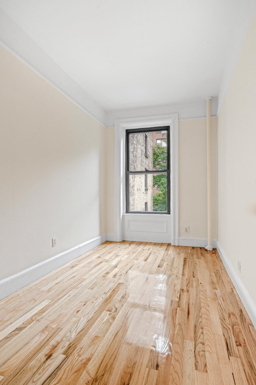 an empty room with wood floors and a window