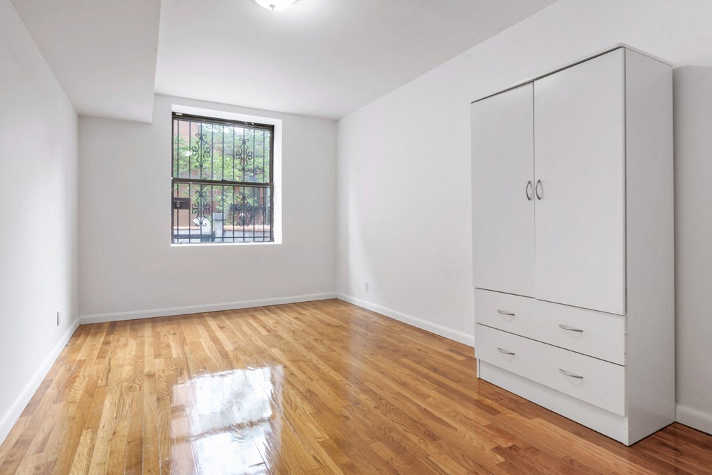 a living room with white walls and wood floors and a window