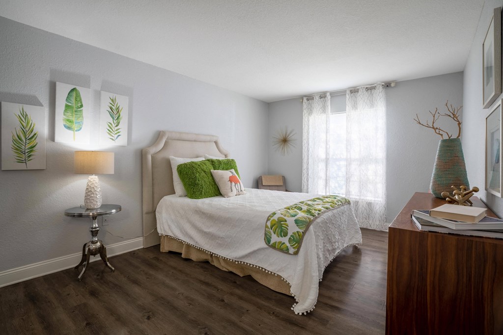 Tampa, FL Apartments – Belara Lakes –bedroom with hardwood flooring and a bed with green pillows