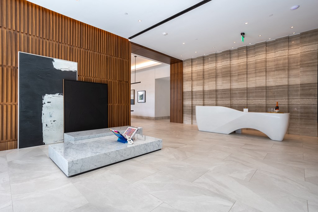 a large lobby with a marble reception desk and a television