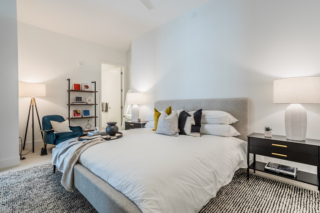 a bedroom with a large bed and a chair and a night stand