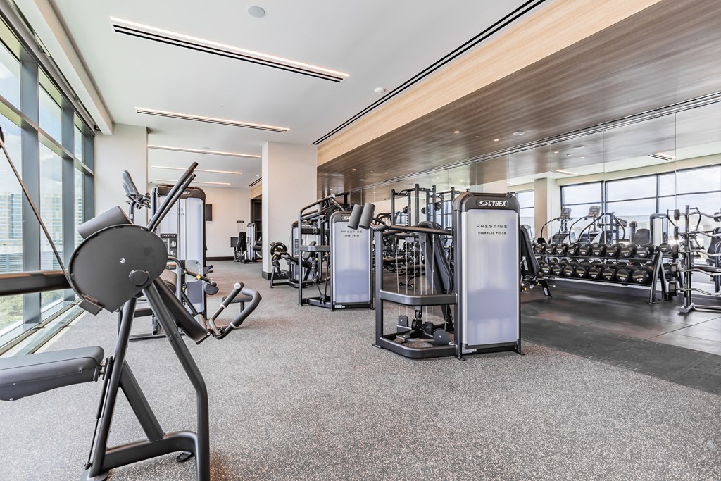 a gym with cardio machines and other exercise equipment in a building with large windows