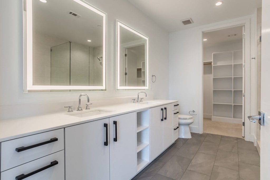 a large white bathroom with two sinks and two mirrors