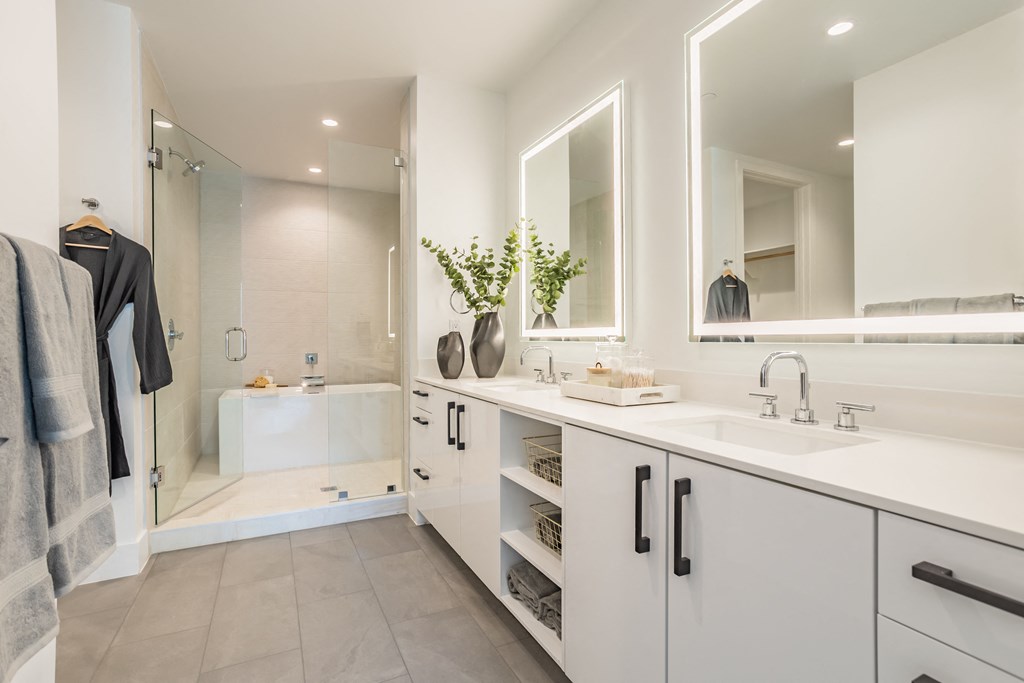 a white bathroom with two sinks and a shower