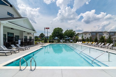 A large swimming pool with lounge chairs and a building in the background.