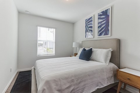 Bright bedroom with queen bed, white linens, blue accent pillow, and blue and white artwork.