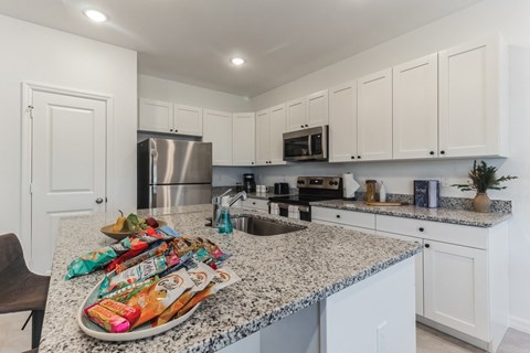 a kitchen with white cabinets and granite counter tops and a sink