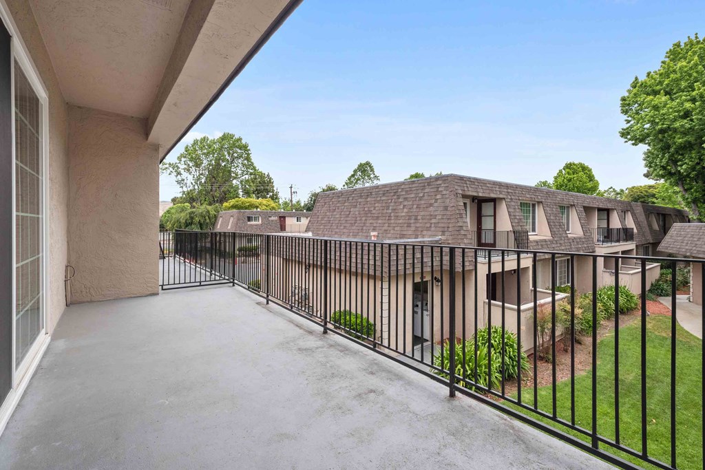 a balcony with a fence and a house on the other side of it