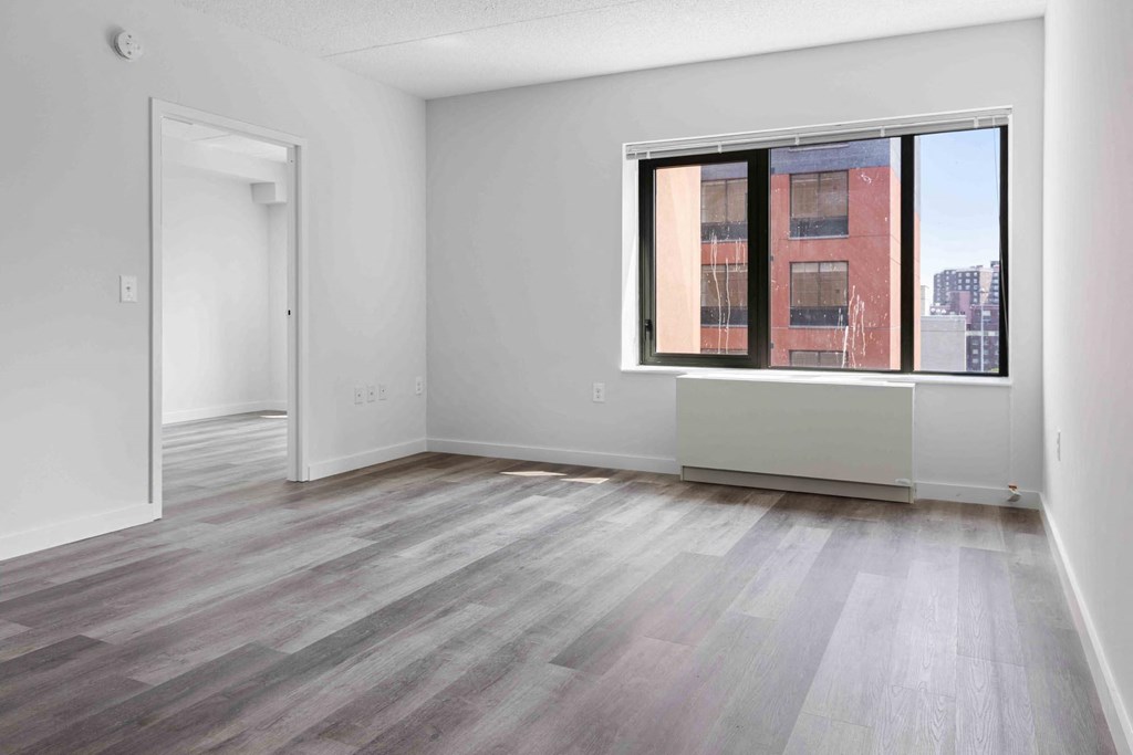 an empty living room with a large window and wooden floors