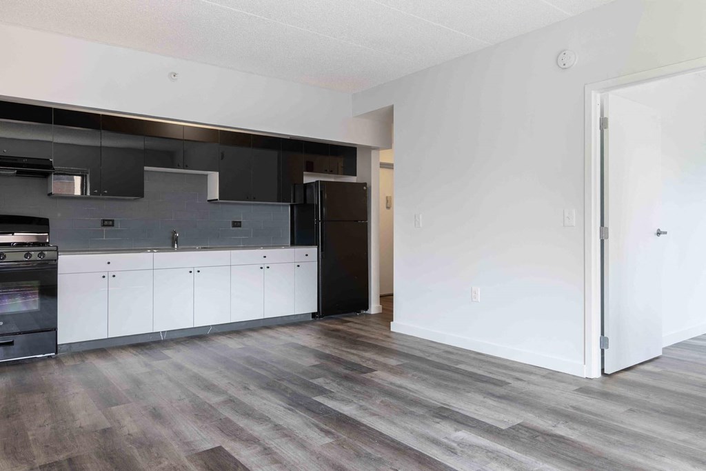 an empty kitchen with white cabinets and black appliances
