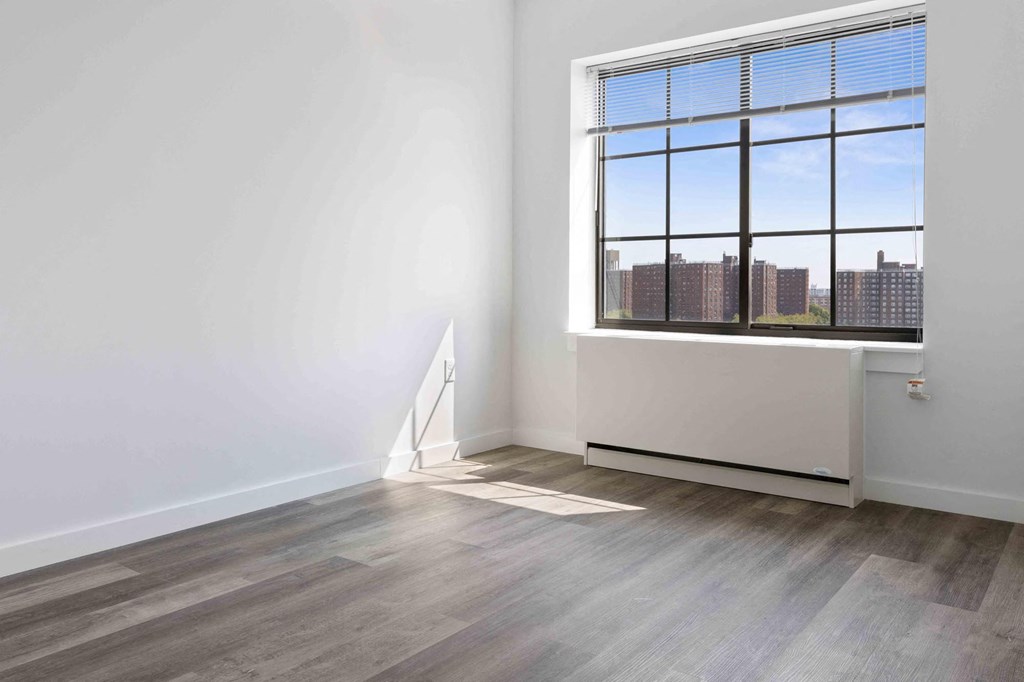 an empty room with a window and wood floors