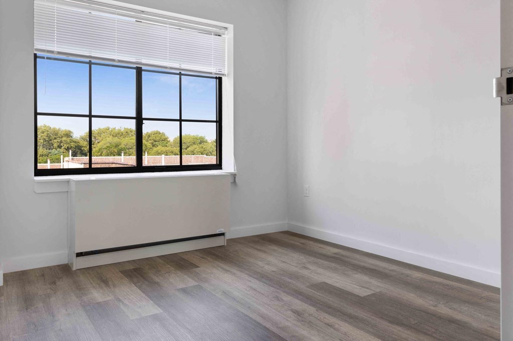 an empty room with a window and wood floors