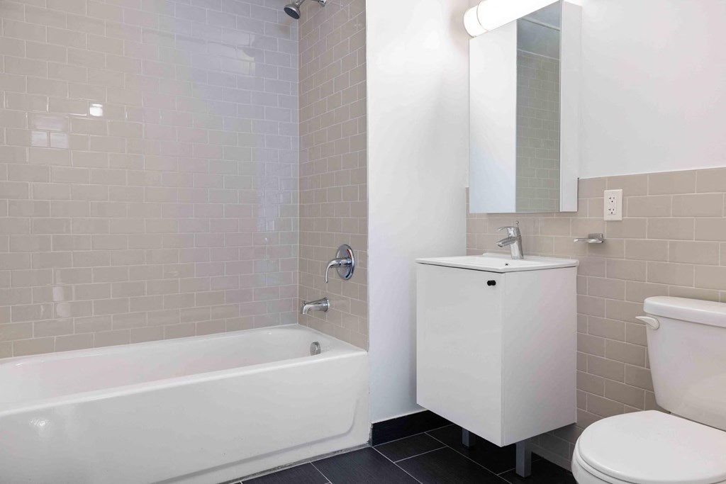 a bathroom with a tub sink and toilet and a mirror