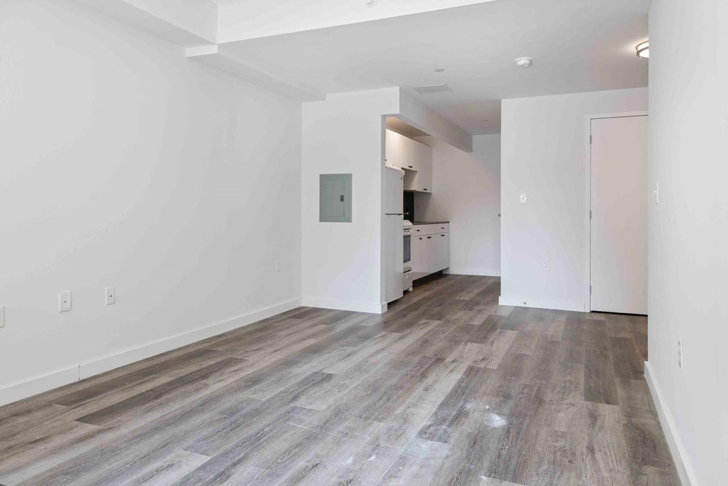 a living room and kitchen with white walls and wood floors