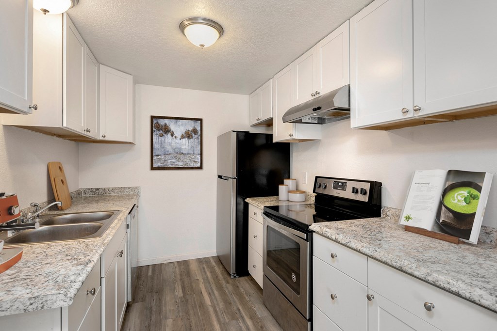 Apartments For Rent In Lynnwood, WA - Evergreen Grove Apartments - Kitchen With White Spacious Countertops, Stainless-Steel Appliances, And Small Potted Plants