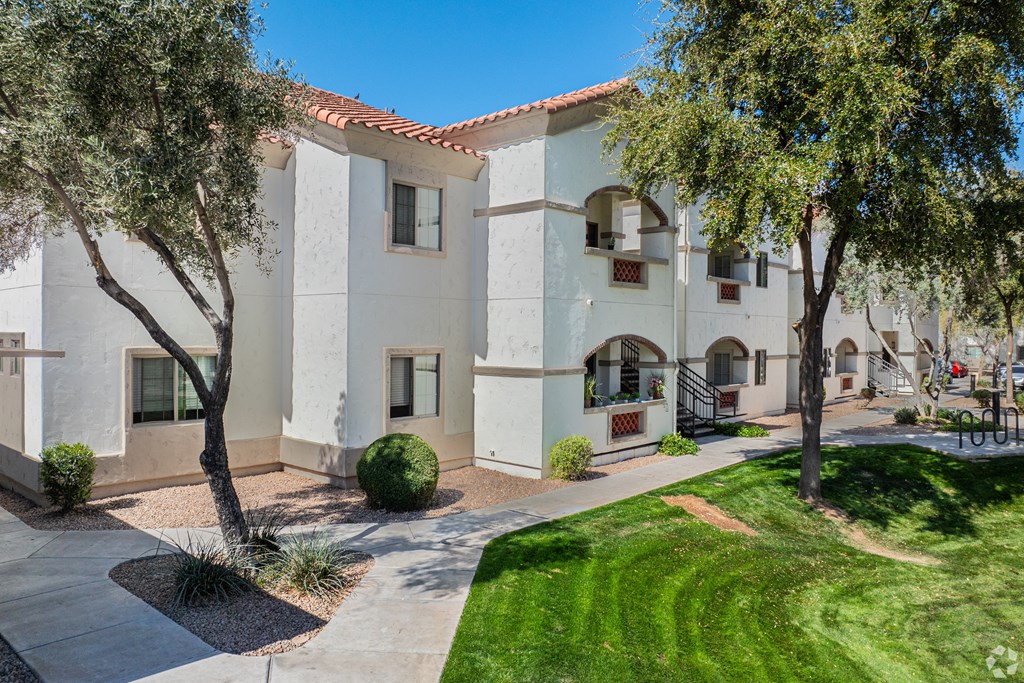 A white building with a red tile roof and a green lawn in front.
