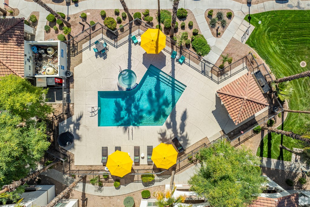 An aerial view of a pool surrounded by yellow umbrellas and palm trees.