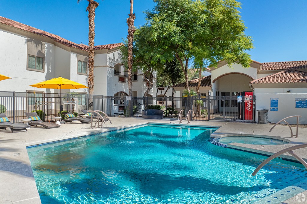A pool with a yellow umbrella and palm trees in the background.