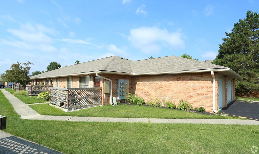the front of a brick house with a sidewalk and grass